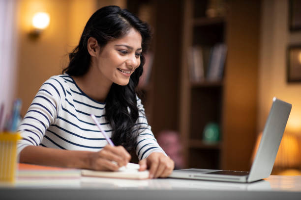 Female student searching for study material from the internet and completing notes