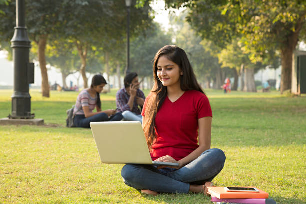 Female student surfing the internet through a laptop in college grounds