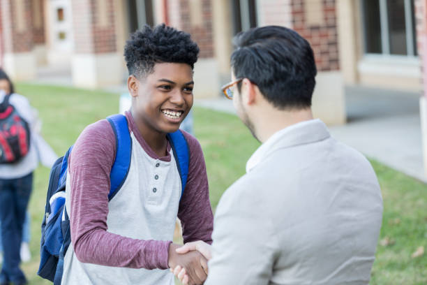 The teacher shaking hands with the student and encouraging them by appreciating them
