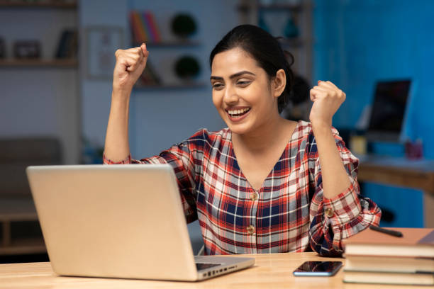 Female student looking at the laptop and expressing happiness at the success