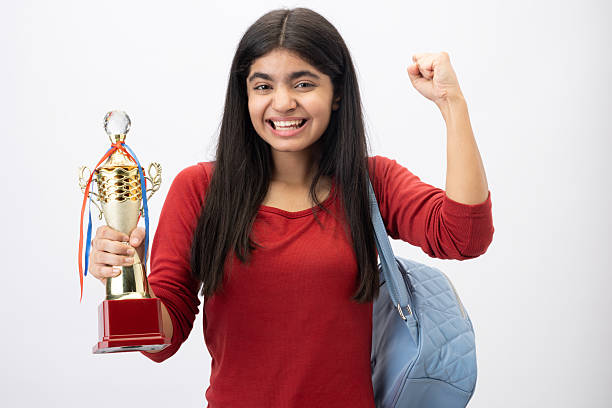The female student expressed happiness on the success by holding the trophy in one hand and standing in the other