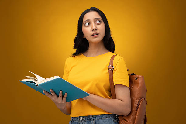 The female student stood with a notebook in her hand,looking elsewhere