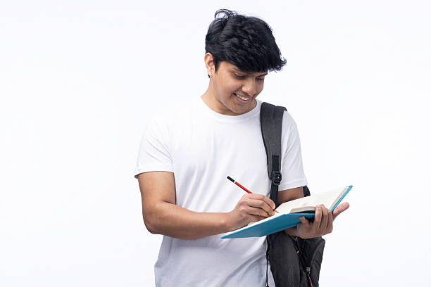 The student is standing and writing some notes in a notebook