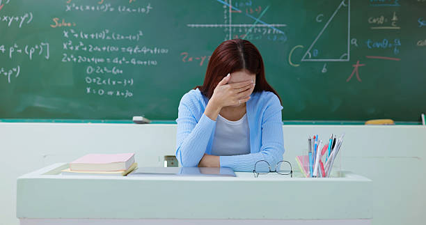 The teacher sat with her hands on her head,upset with teaching mathematics