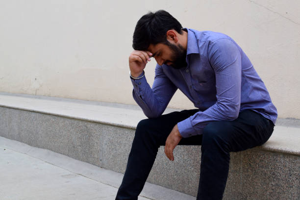 Saddened by unemployment,an educated unemployed person sitting in a public place holding his head