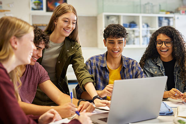 Students gathered together while surfing study material on laptops