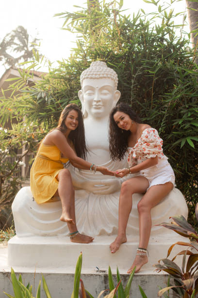 Two female students shake hands near Buddha statue in solidarity