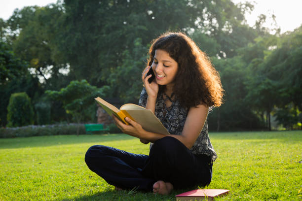 Female student memorizing lessons from book in garden