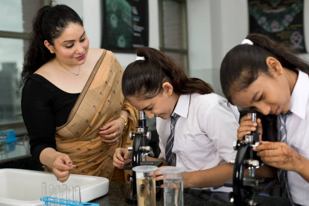 Female teacher, female students getting practical in the physics laboratory