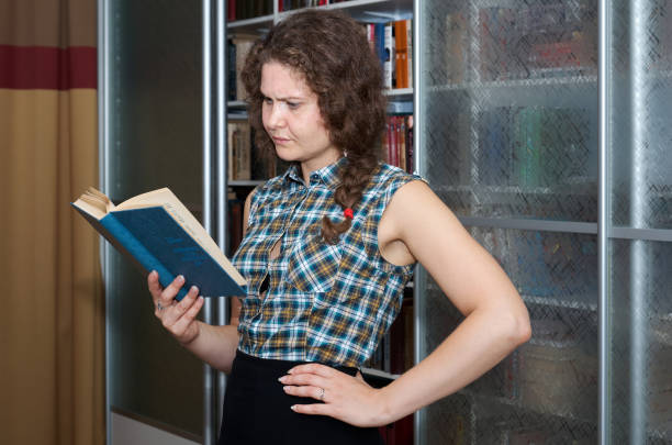 The girl student is studying the book in the reading room with full concentration