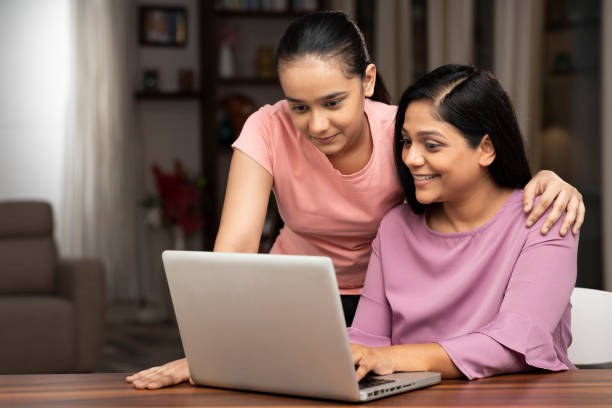 Two sisters are learning the technique of working from a laptop