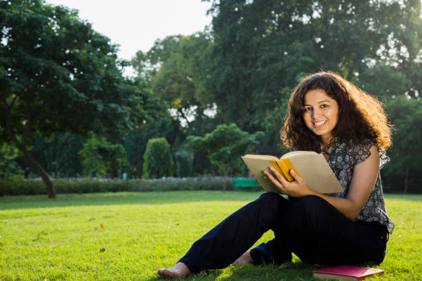 A girl student reads tips on how to make the house beautiful in the book in the college grounds