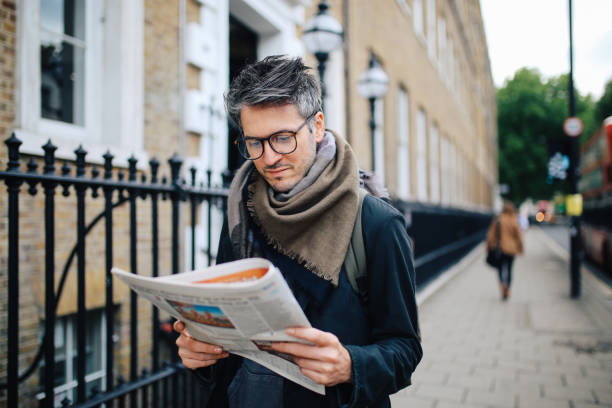 The person reading the newspaper while walking on the road