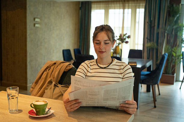 The female student sat comfortably reading the latest news from the newspaper