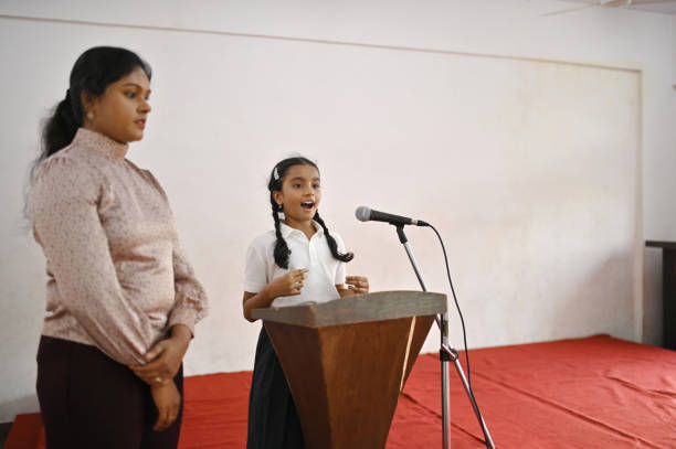 Girl student giving a speech to the microphone in school