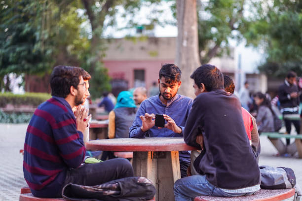 Male students sit in groups in a public place and play reels