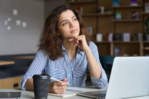 Girl student thinking about essay writing after looking at it from laptop
