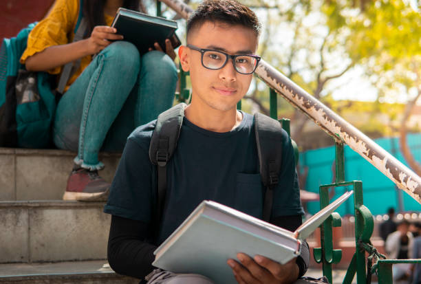 The student sits on the staircase outside the examination hall and studies