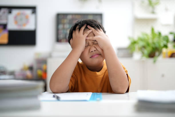 A small child is afraid of math and puts his hands over his eyes
